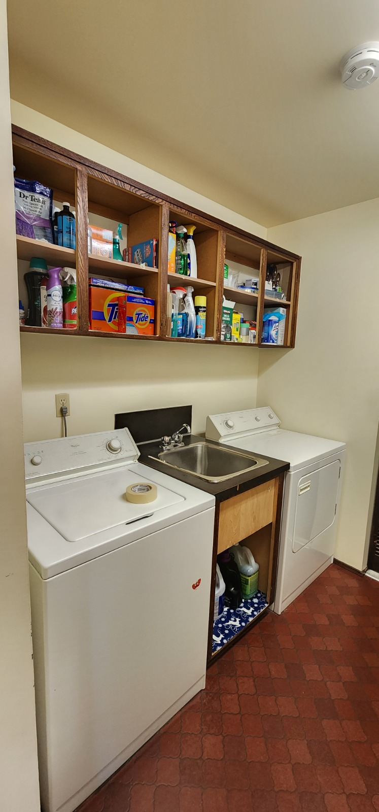 Laundry room before renovation — dated cabinetry and flooring
